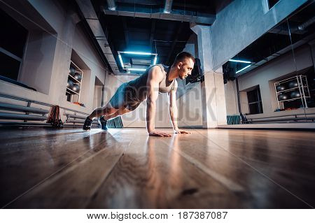 Attractive Muscular Man Doing Push-ups On A Wooden Floor.
