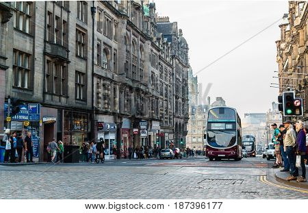 EDINBURGH SCOTLAND - SEPTEMBER 13 2014: Lothian Buses' double decker bus on a crowded North Bridge street while pedestrians wait for a green traffic light to cross the paved street.