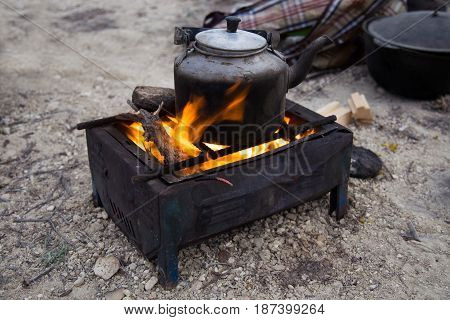 Smoked camping kettle on fire at an outdoor campsite at the dessert