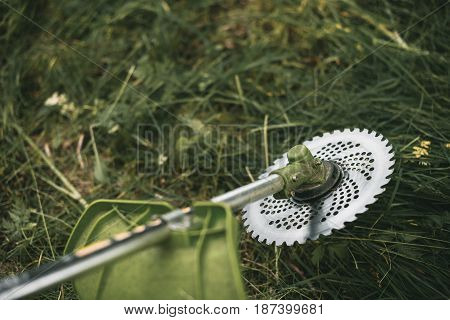 Gasoline Trimmer Head On Green Grass. Round Trimmer Blade.