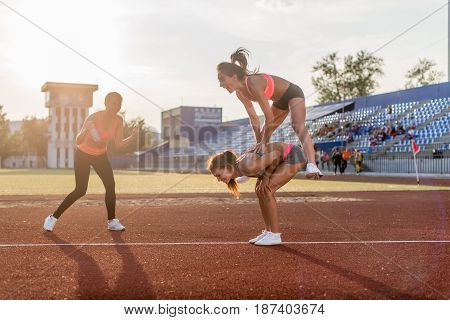 Fit women in the stadium playing leap frog