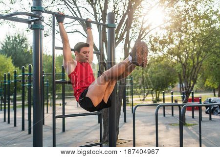 Fitnes man hanging on wall bars performing legs raises. Core cross training working out abs muscles.