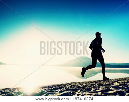 Healthy Lifestyle. Tall Young Man Runner Is Running On Sunrise Seaside. Man Jump In Sand