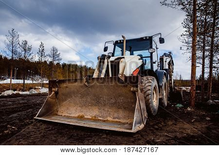 Machine tractor loader with bucket front in front of the sky. Concept road construction.