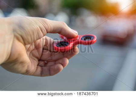 Man playing with fidget spinner stress relieving toy outdoors on city street