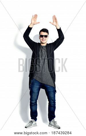Casual young man wearing sunglasses, hands up, bent backwords, happy, positive attitude, full lenght, isolated on white