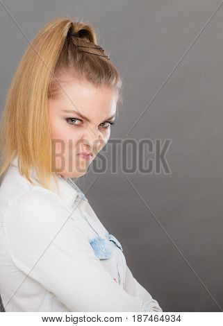 Negative emotion feelings attitude. Angry grumpy young woman looking very displeased standing with arms folded serious face expression on dark
