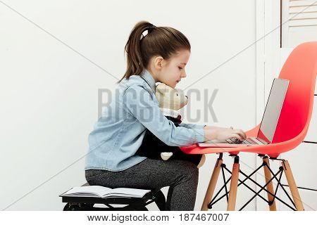 Cute Girl Typing On Laptop With Teddy Bear Toy