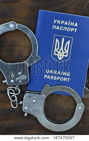 A Ukrainian Passport With Police Handcuffs Lies On A Wooden Table. Problems With The Law During The