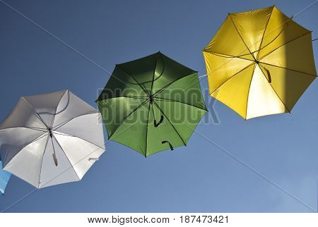 umbrellas of different colors over the street with blue sky as background