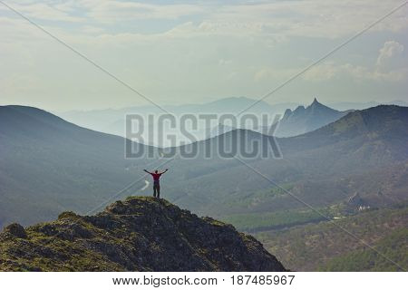 man standing on a cliff in mountains with snowy picks and blue sky with clouds on background