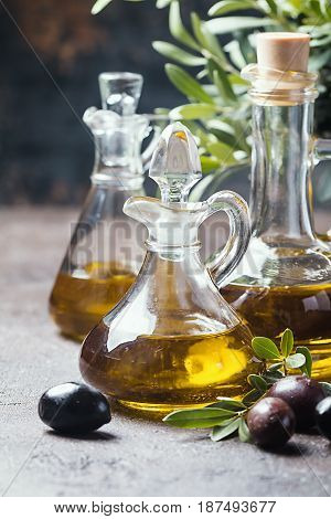 Olive oil in a glass bottle and olive branch on brown stone table