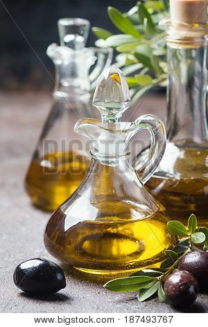 Olive oil in a glass bottle and olive branch on brown stone table
