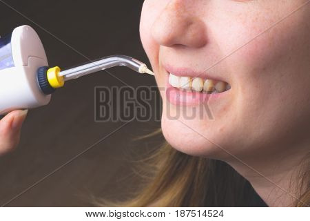 A woman using an oral irrigator in bathroom.