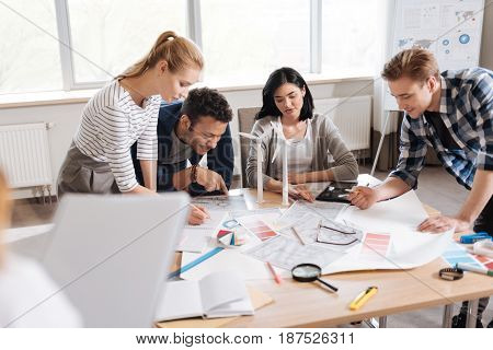 Hard working people. Nice serious professional engineers doing drawings and sitting around the table while being involved in work