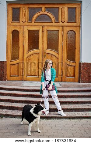 Trendy Girl At Glasses And Ripped Jeans With Russo-european Laika (husky) Dog On A Leash, Against Wo