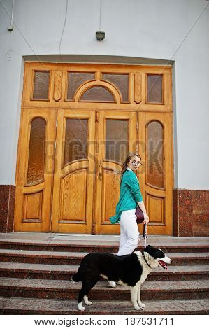 Trendy Girl At Glasses And Ripped Jeans With Russo-european Laika (husky) Dog On A Leash, Against Wo