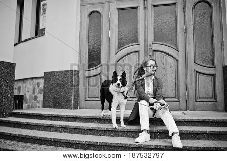 Trendy Girl At Glasses And Ripped Jeans With Russo-european Laika (husky) Dog On A Leash, Against Wo