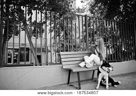 Trendy Girl At Glasses And Ripped Jeans With Russo-european Laika (husky) Dog On A Leash, Against Be