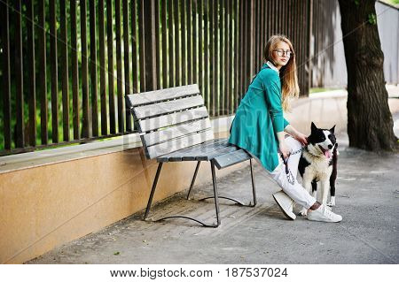 Trendy Girl At Glasses And Ripped Jeans With Russo-european Laika (husky) Dog On A Leash, Against Be