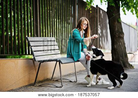 Trendy Girl At Glasses And Ripped Jeans With Russo-european Laika (husky) Dog On A Leash, Against Be