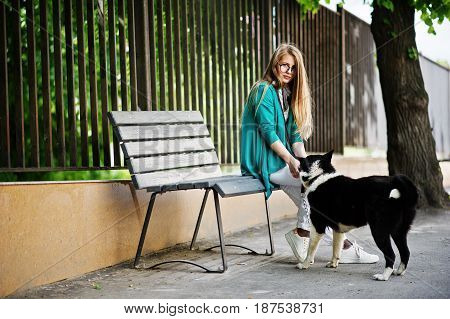 Trendy Girl At Glasses And Ripped Jeans With Russo-european Laika (husky) Dog On A Leash, Against Be