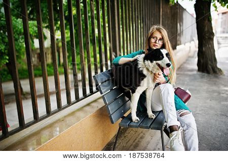 Trendy Girl At Glasses And Ripped Jeans With Russo-european Laika (husky) Dog On A Leash, Against Be