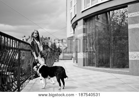 Trendy Girl At Glasses And Ripped Jeans With Russo-european Laika (husky) Dog On A Leash, Against Bu