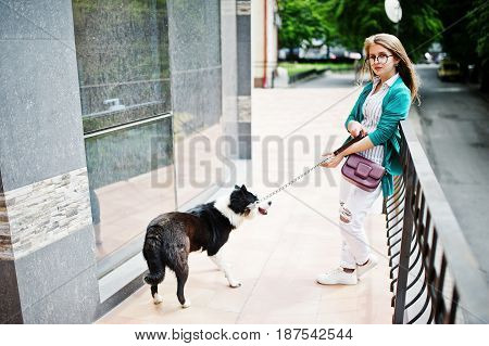 Trendy Girl At Glasses And Ripped Jeans With Russo-european Laika (husky) Dog On A Leash, Against Bu