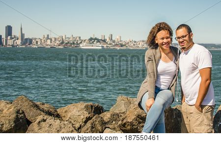 Brother and sister sitting on rocks at Treasure Island with San Francisco view in background