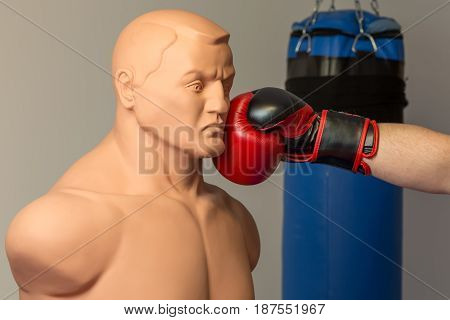 Caucasian Boxer Wearing Red Boxing Gloves Punching Straight On A Dummy Mannequin Doll On A Gym With