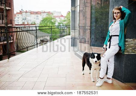 Trendy Girl At Glasses And Ripped Jeans With Russo-european Laika (husky) Dog On A Leash, Against St