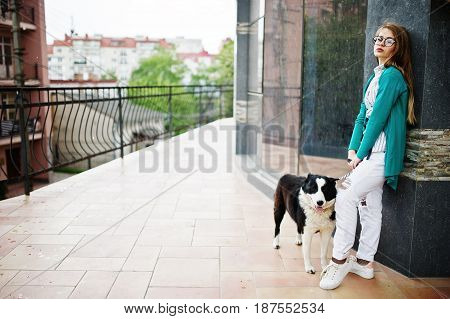 Trendy Girl At Glasses And Ripped Jeans With Russo-european Laika (husky) Dog On A Leash, Against St