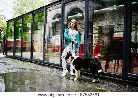 Trendy Girl At Glasses And Ripped Jeans With Russo-european Laika (husky) Dog On A Leash, Against St