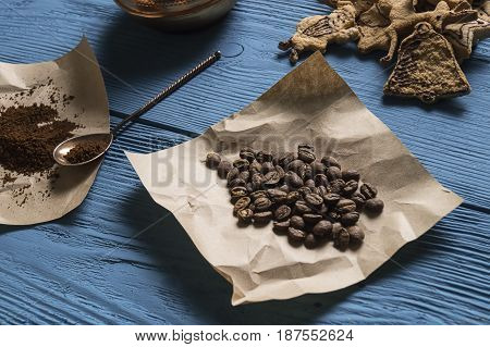 Coffee Beans, Ground Coffee, Silver Spoon On Kraft Paper And Christmas Cookies On The Blue Boards