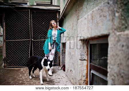 Trendy Girl At Glasses And Ripped Jeans With Russo-european Laika (husky) Dog On A Leash, Against St