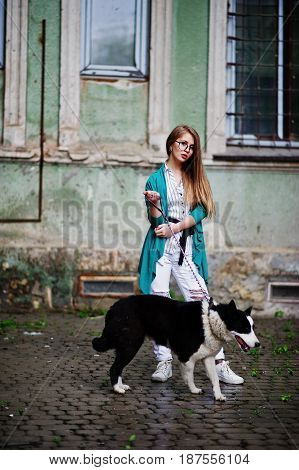 Trendy Girl At Glasses And Ripped Jeans With Russo-european Laika (husky) Dog On A Leash, Against St