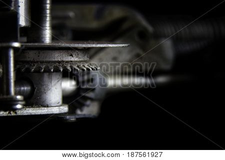 Geared to Type: A gearing mechanism from a classic 1940's typewriter with bokeh to faded black background. Suitable for business and industry advertising applications or as a wall decoration in business offices and hotel rooms that cater to the business c