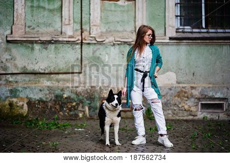 Trendy Girl At Glasses And Ripped Jeans With Russo-european Laika (husky) Dog On A Leash, Against St