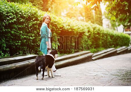 Trendy Girl At Glasses And Ripped Jeans With Russo-european Laika (husky) Dog On A Leash, Against St