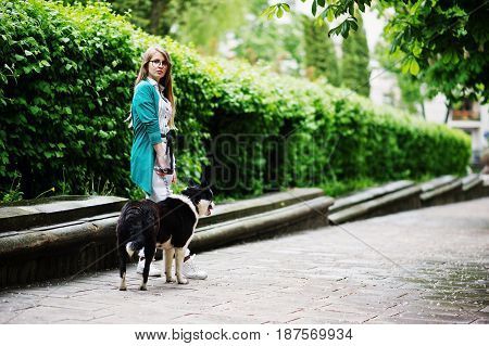 Trendy Girl At Glasses And Ripped Jeans With Russo-european Laika (husky) Dog On A Leash, Against St