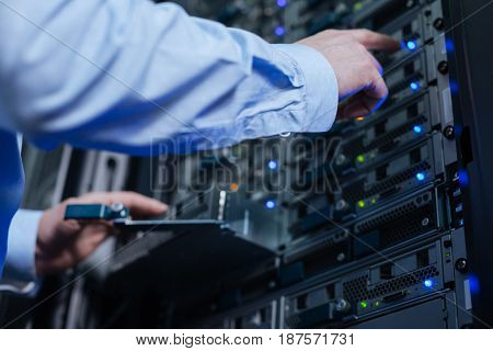 Standard setting up. Selective focus of a male hand pressing the button on the network server while doing the setting up