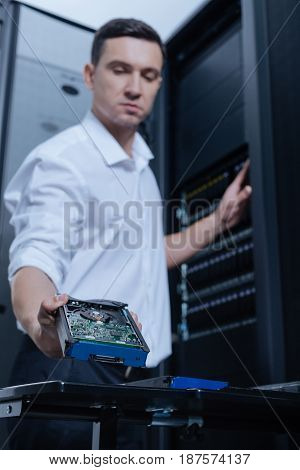 For information storage. Selective focus of a hard drive being taken by a professional male technician while working in the server room
