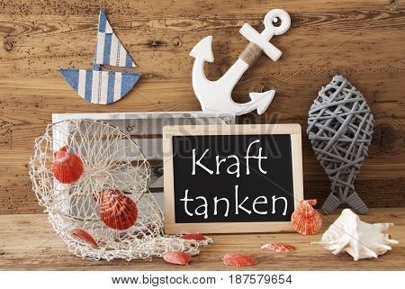 Blackboard With Nautical Summer Decoration And Wooden Background. German Text Kraft Tanken Means Relax. Fish, Anchor, Shells And Fishnet For Maritime Contex.