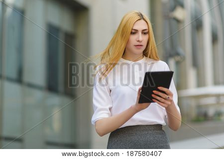 serious businesswoman using tablet pc in front of office building.
