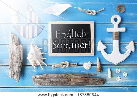 Flat Lay Of Chalkboard On Blue Wooden Background. Sunny Nautic Or Maritime Summer Decoration As Holiday Greeting Card. German Text Endlich Sommer Means Happy Summer