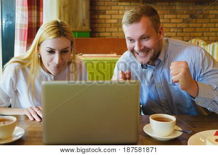 Business meeting in a cafe. Man and woman Looking at the laptop. They are happy and successful.