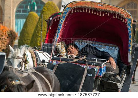 Esfahan, Iran - December 13, 2015: Iranian man sleeps in traditional old fashioned fiacre, horse-driven carriage in Esfahan, Iran.