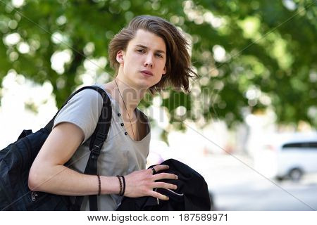Portrait of young handsome man, city outdoor. Attractive trendy fashion 18 years old teen boy posing outside