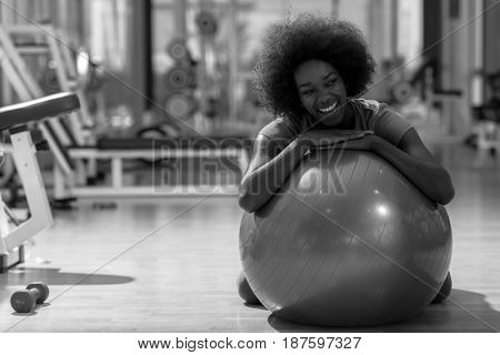 happy african american woman with a curly afro hairstyle in a  gym relaxing after pilates workout
